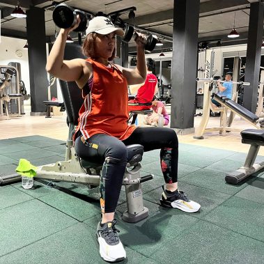 Seorang member wanita di BisaFitness sedang berlatih shoulder press menggunakan dumbbell di area gym yang bersih dan tertata rapi. Latihan ini melatih kekuatan bahu dan postur tubuh bagian atas. BisaFitness adalah gym dan fitness center di Batam yang ramah pemula, bersih, dan affordable, dengan dua cabang terdekat di Tiban dan Batam Center.