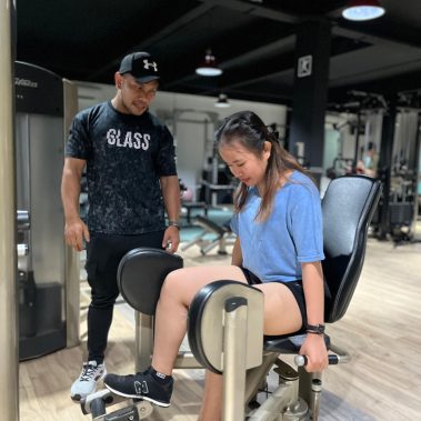 Seorang personal trainer di BisaFitness sedang membimbing member wanita berlatih menggunakan mesin Hip Adductor untuk memperkuat otot paha bagian luar. Latihan dilakukan di ruang gym yang luas, bersih, dan nyaman dengan peralatan lengkap. BisaFitness adalah gym dan fitness center di Batam yang ramah pemula, bersih, dan affordable, dengan dua cabang terdekat di Tiban dan Batam Center.
