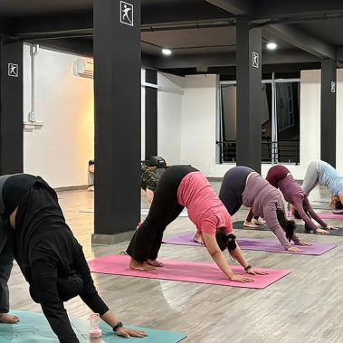 Suasana kelas yoga di BISA Fitness Batam Center dengan para member yang sedang melakukan pose Downward Dog secara serempak di studio bersih dan luas. BISA Fitness merupakan gym dan fitness center yang ramah pemula, bersih, dan affordable dengan dua cabang terdekat di Tiban dan Batam Center.