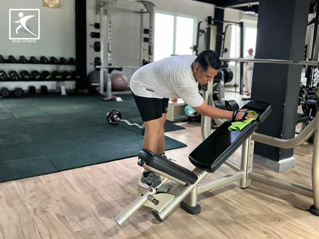 Member BisaFitness di Batam mengelap bench press setelah latihan, mencerminkan budaya gym yang bersih, rapi, dan ramah pemula di cabang Tiban maupun Batam Center.